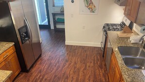 A kitchen with wooden cabinets, a stainless steel refrigerator, a granite countertop, and a sink.