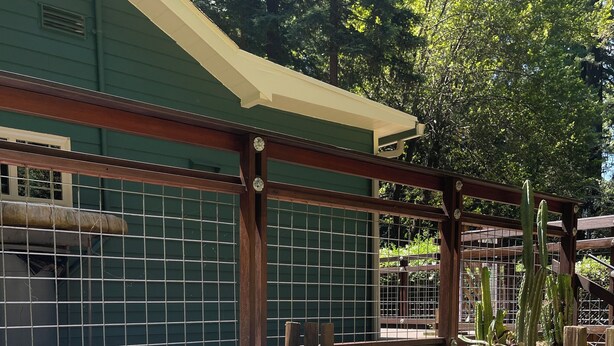 A hot tub area with a wooden deck, a fenced enclosure, and potted plants.
