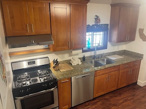 A kitchen with wooden cabinets, a stainless steel stove, a dishwasher, and a granite countertop. - Perfect 2-bedroom cabin in Felton for a relaxing getaway. Hot tub + pet welcome (Felton)
