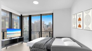 A modern hotel room with a large bed, a TV, and a city view. - Contemporary Haven with Glass Views 2BR | Miami (Miami)