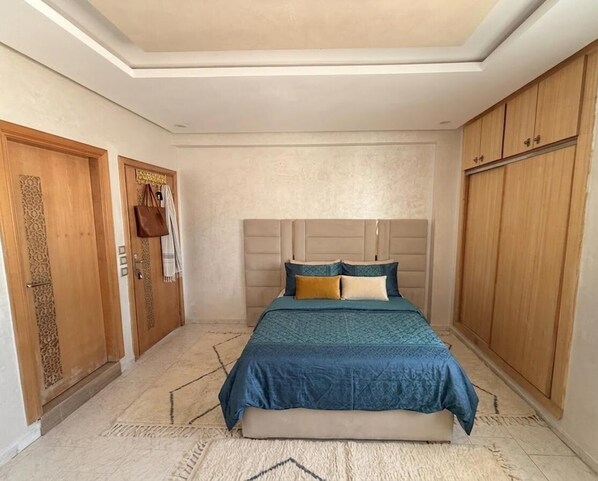 A bedroom with a bed, wooden wardrobe, and a headboard.