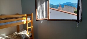 Una habitación con literas, una ventana con vistas a montañas y un cuadro colgado en la pared.