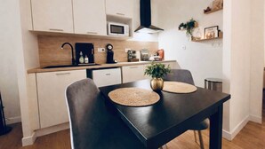 Una cocina moderna con gabinetes blancos, microondas, cafetera y una campana extractora negra.