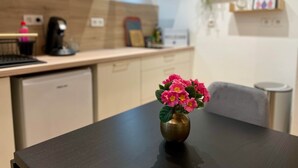 Una cocina con microondas, cafetera y un florero con flores sobre una mesa.