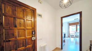 Een houten deur met een veiligheidsslot, een witte radiator, en een gang die leidt naar een balkon met buitenmeubilair.