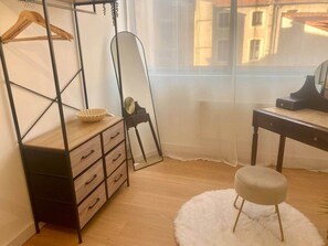 Una habitación con un aparador de madera, un espejo, un taburete redondo y una mesa con una lámpara.