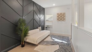 Un dormitorio moderno con cabecera de diseño geométrico, cama con edredón de color claro, alfombra con estampado de cebra y una planta en maceta.