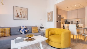 Una sala de estar moderna con un sofá, un sillón amarillo, una mesita de centro y un comedor con una mesa y sillas.