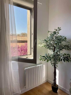 Una habitación con ventana, radiador y planta en maceta.