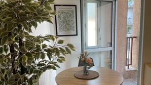 Une table ronde en bois, ornée d’un vase de fleurs, d’une plante en pot et d’une estampe botanique encadrée accrochée au mur.