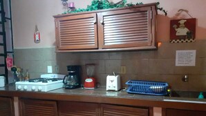 Una cocina con estufa a gas, cafetera, licuadora, tostadora y un escurreplatos azul.