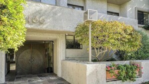 Entrada de un edificio con una puerta grande, el número '166' arriba y una pequeña ventana a la derecha.