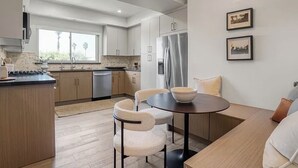 Una cocina moderna con comedor, armarios de madera, un refrigerador y una mesa de comedor con sillas.
