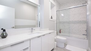 A modern bathroom with a glass shower enclosure, a white sink, and a large mirror. - Modern Comfort 2BR in Delta - Near Parks & Shops (Delta)