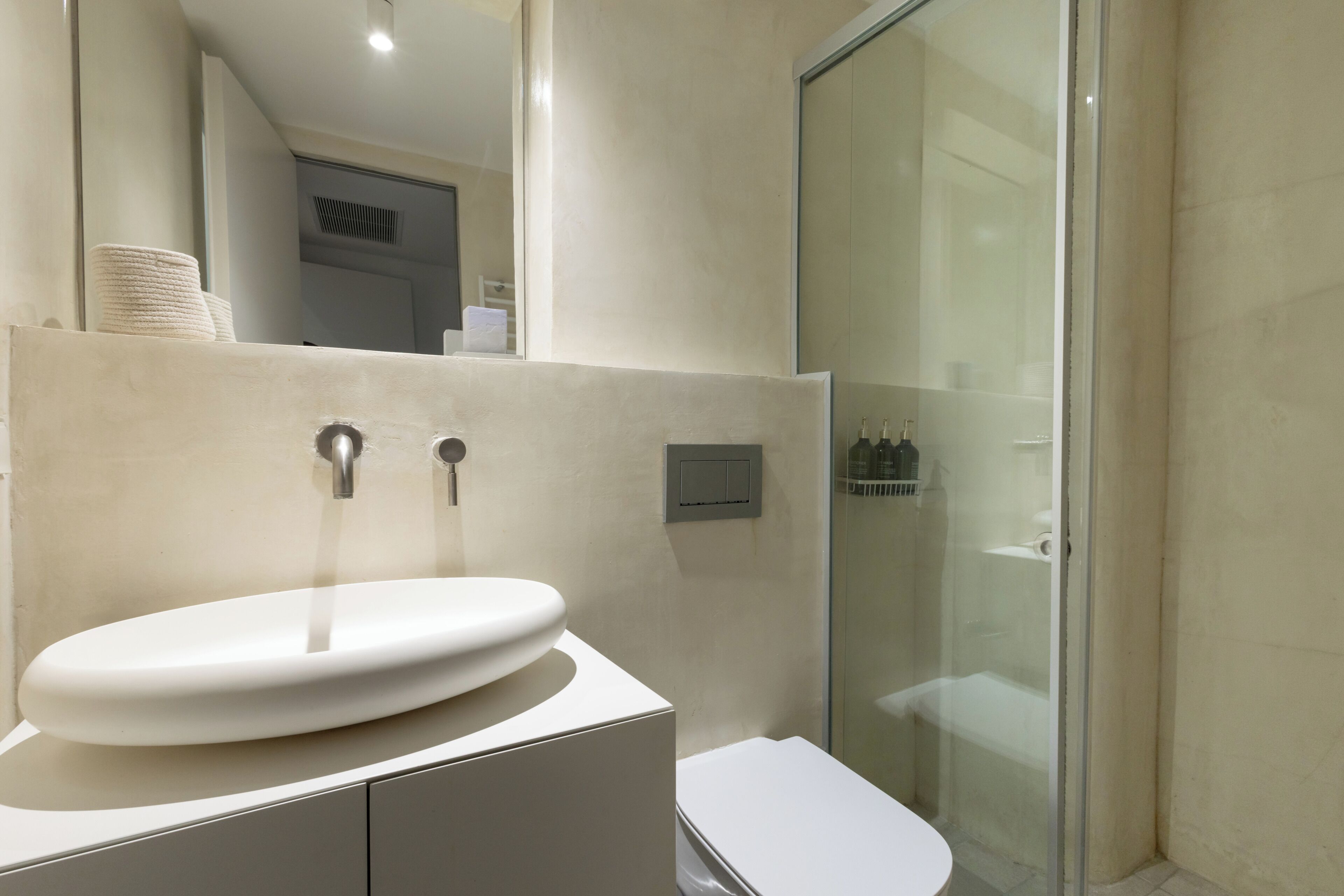 Un bagno moderno con lavandino bianco, un water e box doccia in vetro.