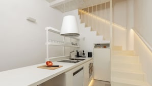 Een moderne keuken met witte kasten, een ingebouwd fornuis en een trap met geïntegreerde verlichting.