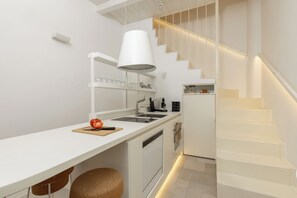 Eine moderne Küche mit weißen Schränken, einem eingebauten Herd und einer Treppe mit integrierter Beleuchtung.