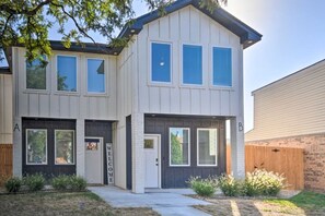 Een woonhuis met twee verdiepingen, een garage, een voordeur en een klein portaaltje.