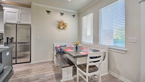 A modern kitchen with a stainless steel refrigerator, a dining table with chairs, and a decorative wreath on the wall. - Bright Amarillo Townhome with Yard and Garage (Amarillo)