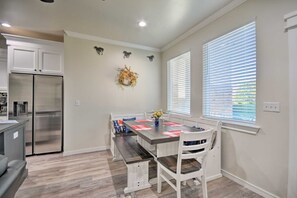 Een moderne keuken met een roestvrijstalen koelkast, een eettafel met stoelen en een decoratieve krans aan de muur.