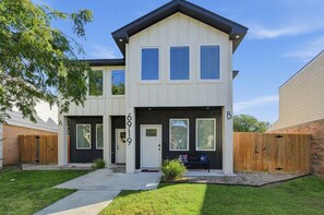 A two-story residential building with a front porch, a mailbox, and a number '6919' on the door. - Bright Amarillo Townhome with Yard and Garage (Amarillo)