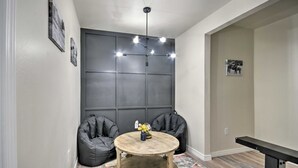 A room with a dark wall panel, a round wooden table with a vase, two black bean bags, and a ceiling light fixture. - Bright Amarillo Townhome with Yard and Garage (Amarillo)