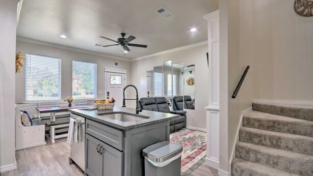 A modern kitchen with a central island, a dining area with a table and chairs, a living room with a sofa and a fireplace, and a staircase leading to an upper level. - Bright Amarillo Townhome with Yard and Garage (Amarillo)
