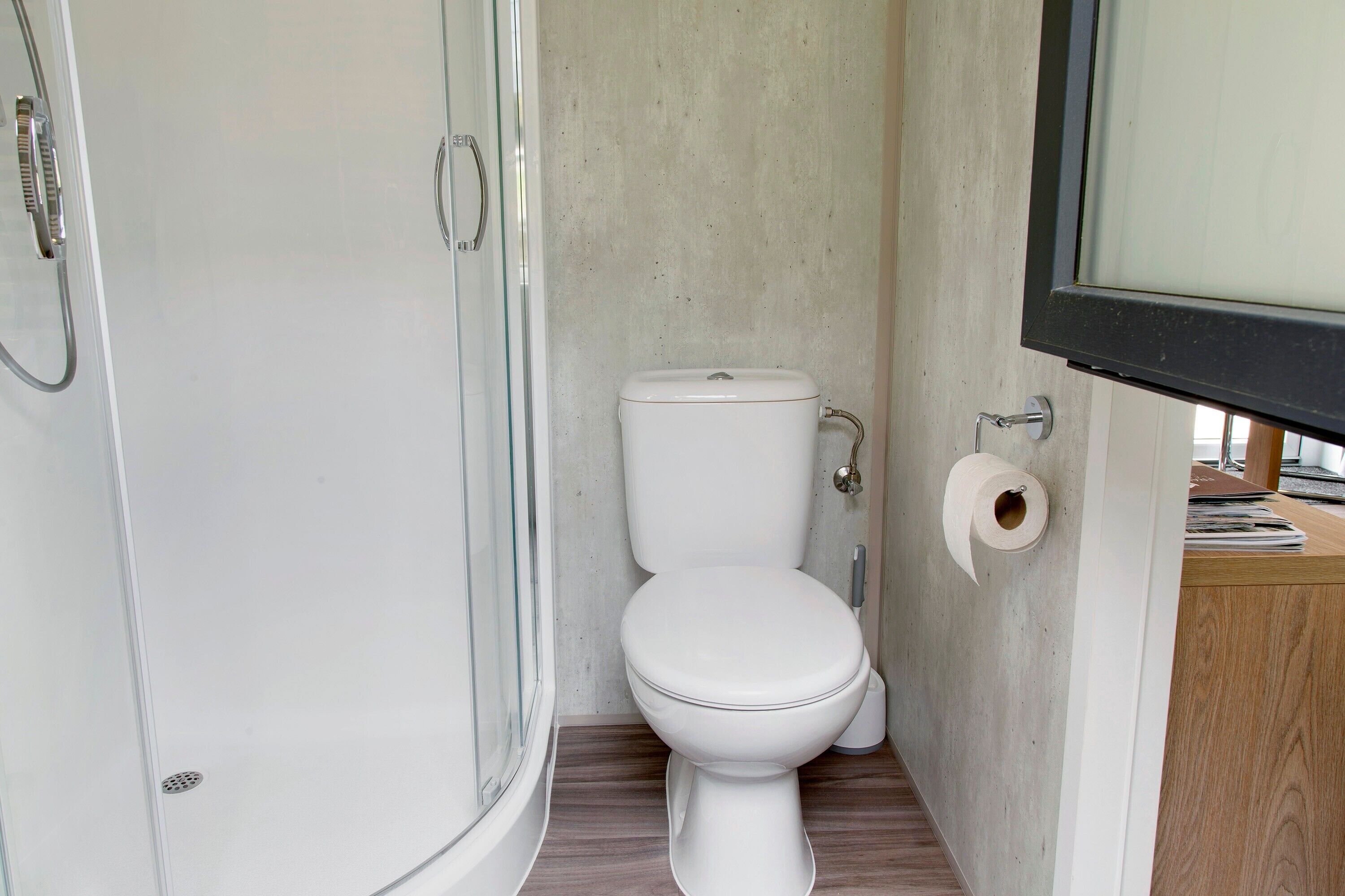 Un bagno con il water, una doccia e un portasciugamani di carta.
