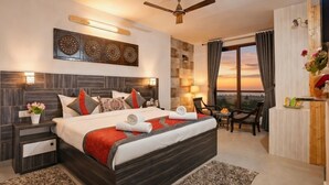 A modern hotel room with a large bed, a ceiling fan, a desk, and a view of the sunset. - Panoramic Views 4-bedroom Luxury villa in marvelous Mukteshwar for your getaway (Mukteshwar)