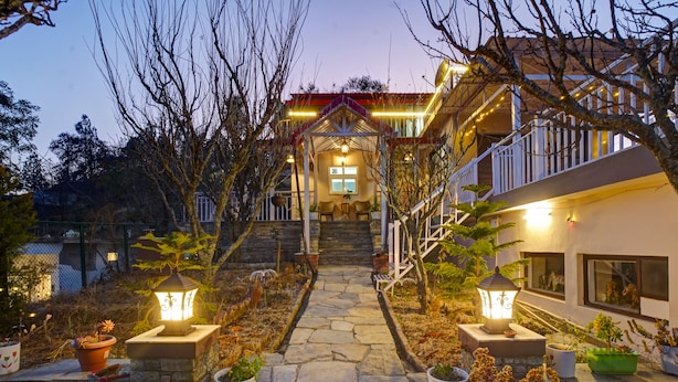 A stone pathway leading to a building with a covered entrance, outdoor lighting, and potted plants. - Panoramic Views 4-bedroom Luxury villa in marvelous Mukteshwar for your getaway (Mukteshwar)