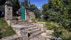 A stone staircase leading to a green door, surrounded by greenery and trees. - Panoramic Views 4-bedroom Luxury villa in marvelous Mukteshwar for your getaway (Mukteshwar)