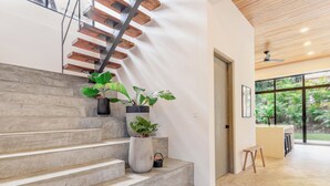 A modern staircase with wooden steps and metal railings, leading to a room with a large window overlooking a garden.