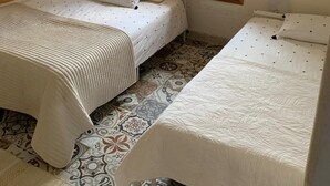 Un dormitorio con dos camas, un armario de madera y una ventana con contraventanas.