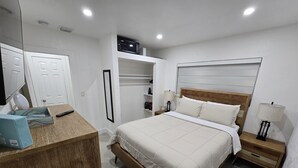 Ein Schlafzimmer mit einem Bett, Nachttischen, einem Kleiderschrank und einem Spiegel.