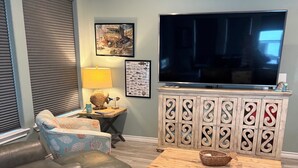 Ein Wohnzimmer mit einer Couch, einem Couchtisch, einem Fernseher und einer Kommode mit Dekorationselementen.