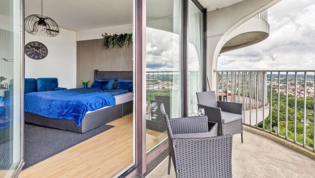 Ein modernes Schlafzimmer mit einem Bett, einer Uhr und einem Balkon mit Blick.