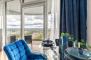 Ein Balkon mit blauem Stuhl, einem Glastisch und Blick auf die Stadt.