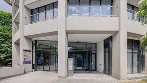 Ein modernes Gebäude mit Glastür, einem sichtbaren Aufzug und einem Schild, das es als Hotel kennzeichnet.