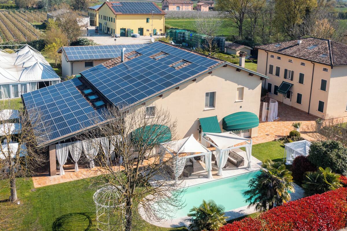 A residential property with solar panels, a swimming pool, and a garden.