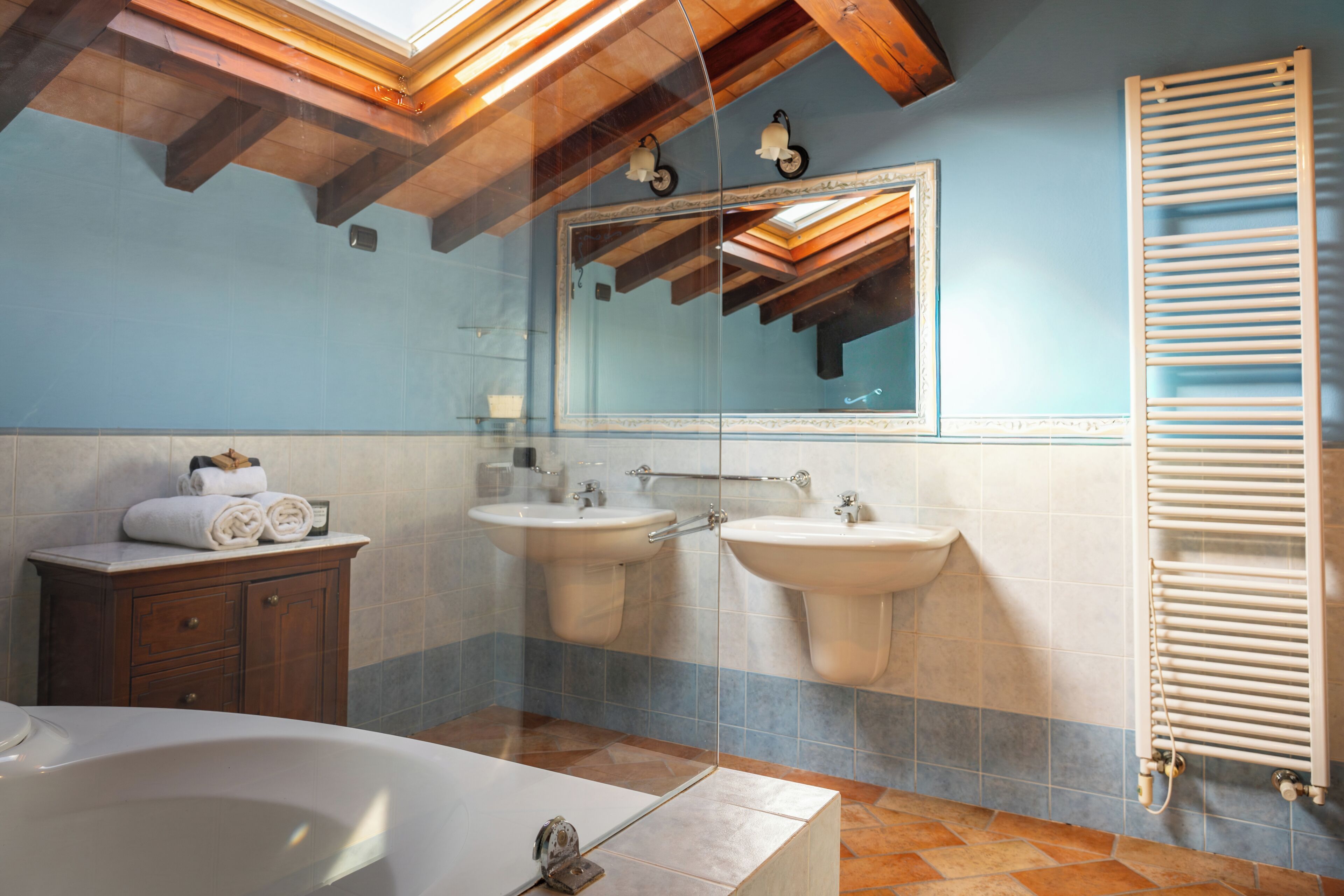 Un baño con bañera, dos lavamanos, un mueble de tocador y un perchero para toallas.