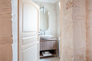 A bathroom with a wooden vanity, a large mirror, and a white sink. - Trullo in Alberobello apartment for 4/6 people (Alberobello)