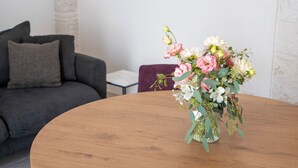 A round wooden table with a floral arrangement in a clear glass vase. - Trullo in Alberobello apartment for 4/6 people (Alberobello)
