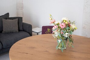 A round wooden table with a floral arrangement in a clear glass vase. - Trullo in Alberobello apartment for 4/6 people (Alberobello)