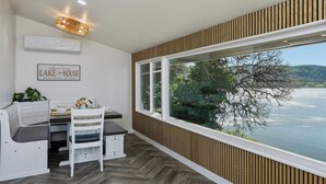 A dining area with a view of a lake, a sign reading 'Welcome to our Lake House,' and a ceiling light fixture.