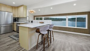 A modern kitchen with a large island, bar stools, and a view of a lake.