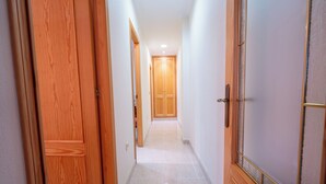 Un corridoio con porte in legno e pavimento piastrellato.