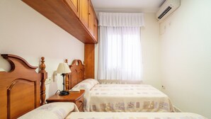 Una camera da letto con due letti, testiere in legno, un comodino con una lampada e una finestra con tende.