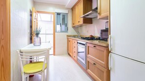 Cucina con mobili in legno, fornello, forno e frigorifero.