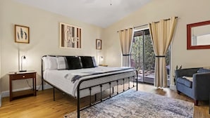 Een slaapkamer met een bed, nachtkastjes, een vloerkleed, een bank en uitzicht op het omliggende landschap.