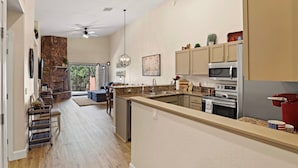 Een moderne keuken met een centraal eiland, inbouwapparatuur en een wand met stenen accenten.